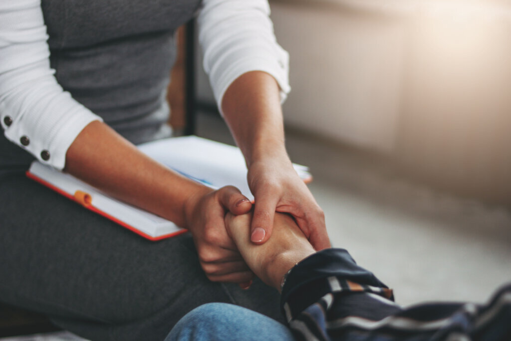 Woman support and help concept. Women hold each other's hands sitting in modern loft office