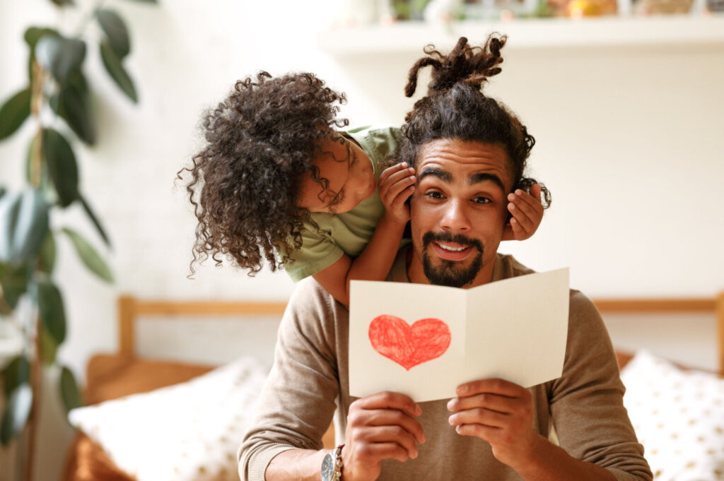 Smiling afro american boy son covering eyes of father with hands and congratulating him on holiday