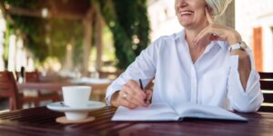 Happy senior woman writing to notebook or diary at a cafe