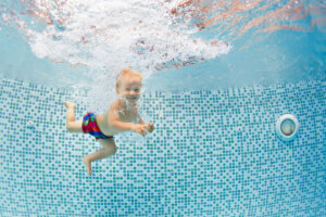 Happy child dive underwater with fun in swimming pool