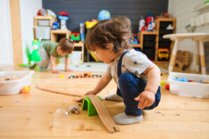 Little boys play with a wooden railroad in a stylish nursery.