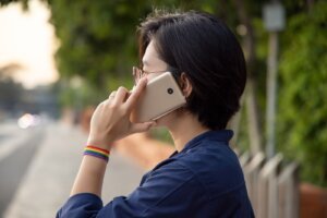 Modern LGBT woman with ribbon symbol using smartphone; concept of LGBT or LGBTQ people community, friends, partner; lgbt rights campaign, equality, same sex marriage, sex preference diversity