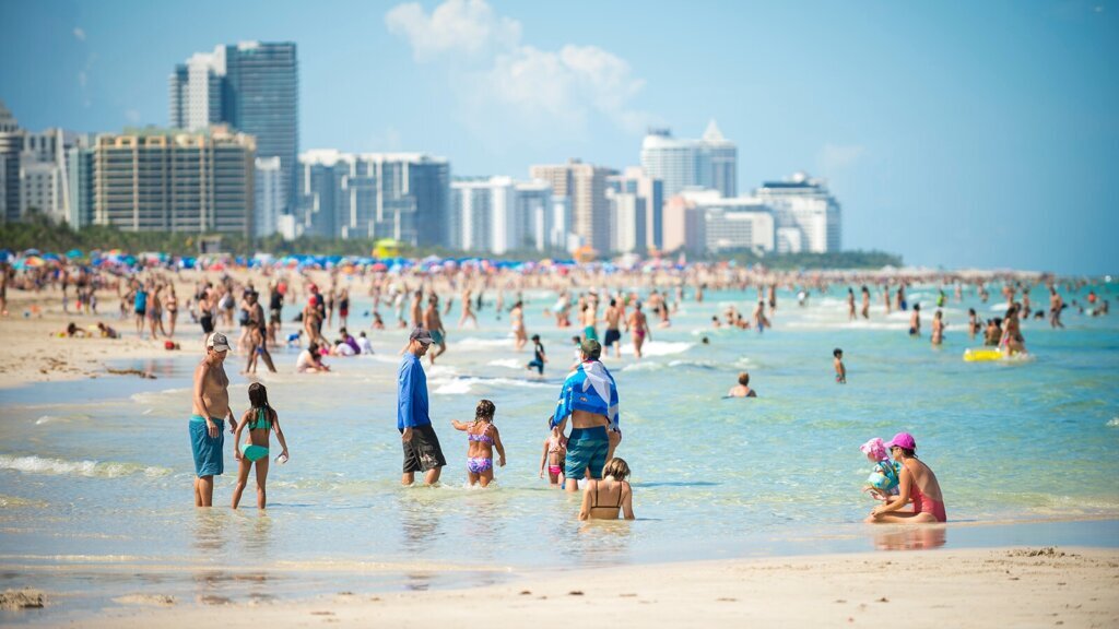Crowds of people enjoy the sea and sand of South Beach on a hot