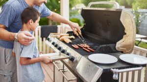 Father teaching son how to grill hot dogs and bonding