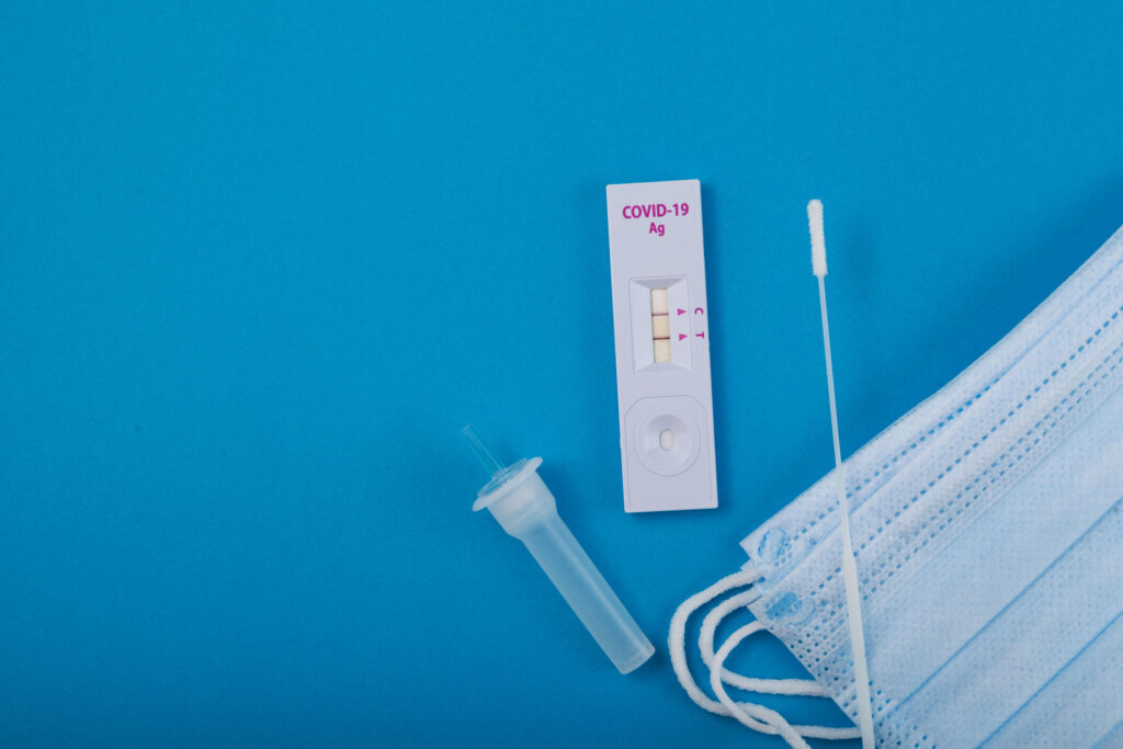 Rapid test for Covid 19 Coronavirus, positive result. Laboratory kit for self testing at home. Blue paper background, copy space