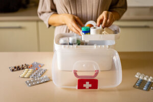 Closeup female hand placing medicament domestic first aid kit. Storage organization emergency supply