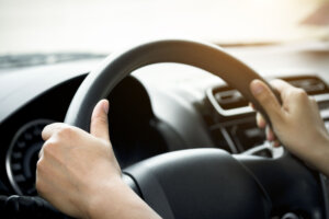 A woman's hand holding a car steering wheel,represents the correct car steering wheel. In order to prevent accidents. Show driving safe step.