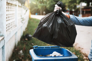 Hand holding garbage black bag putting in to trash