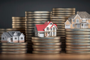 Houses of different size with different value on stacks of coins. Concept of property, mortgage and real estate investment.