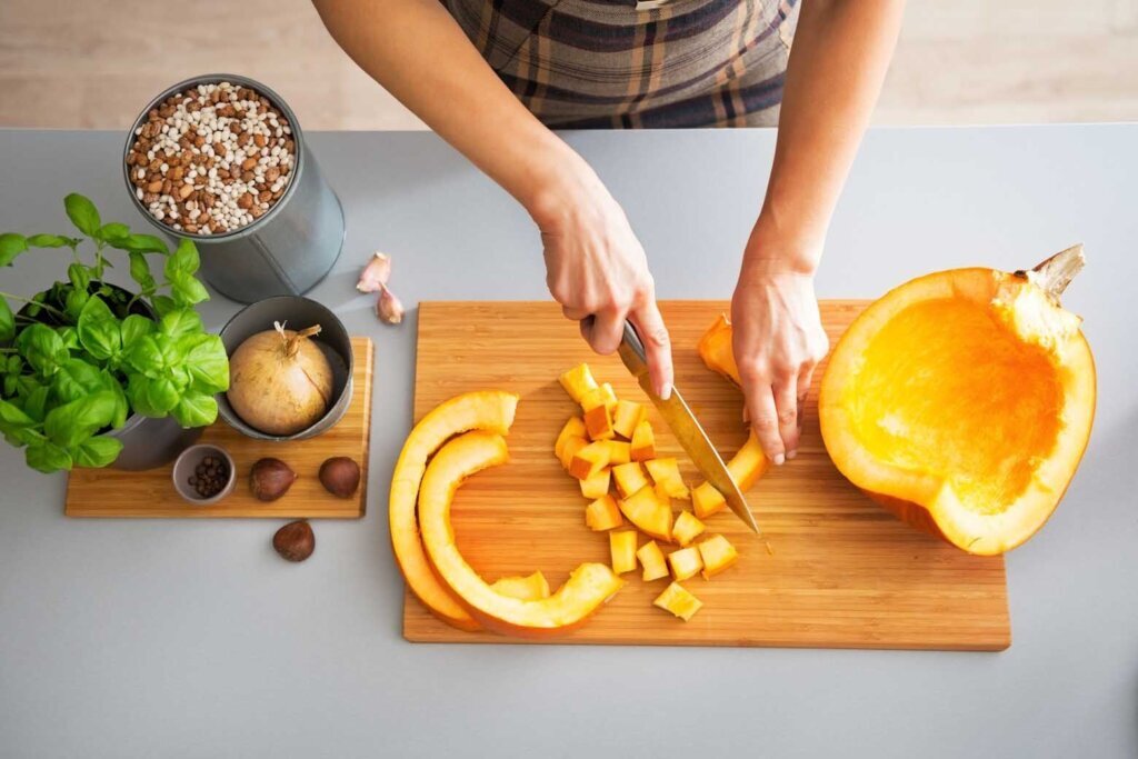 Closeup on young housewife cutting pumpkin
