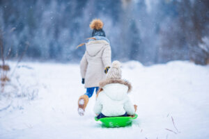 Little adorable girls enjoy a sleigh ride. Child sledding