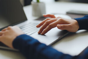 Closeup business people finger using laptop trackpad, touchpad scrolling on website, surfing, searching, browsing the internet