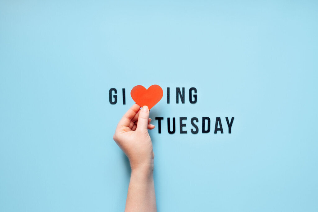 Giving Tuesday, Give, Help, Donation, Support, Volunteer concept with red heart in female hands and text Giving Tuesday on blue background. Its time to give