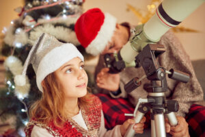 Father and daughter looking at the telescope at Christmas / New Year's day.