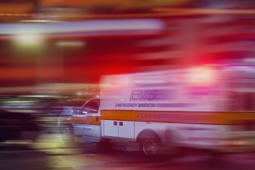 An ambulance speeding through traffic at nighttime