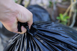 Young man taking out garbage in black plastic bag