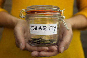 Woman collecting money for charity and holds jar with coins.