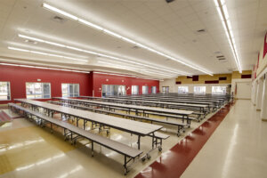 Long tables in an empty red and beige high school cafeteria