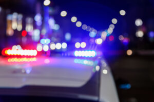 Defocused photo of police car lights in night city with selective focus and bokeh