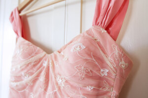 Close up of pink wedding dress hanging on white door