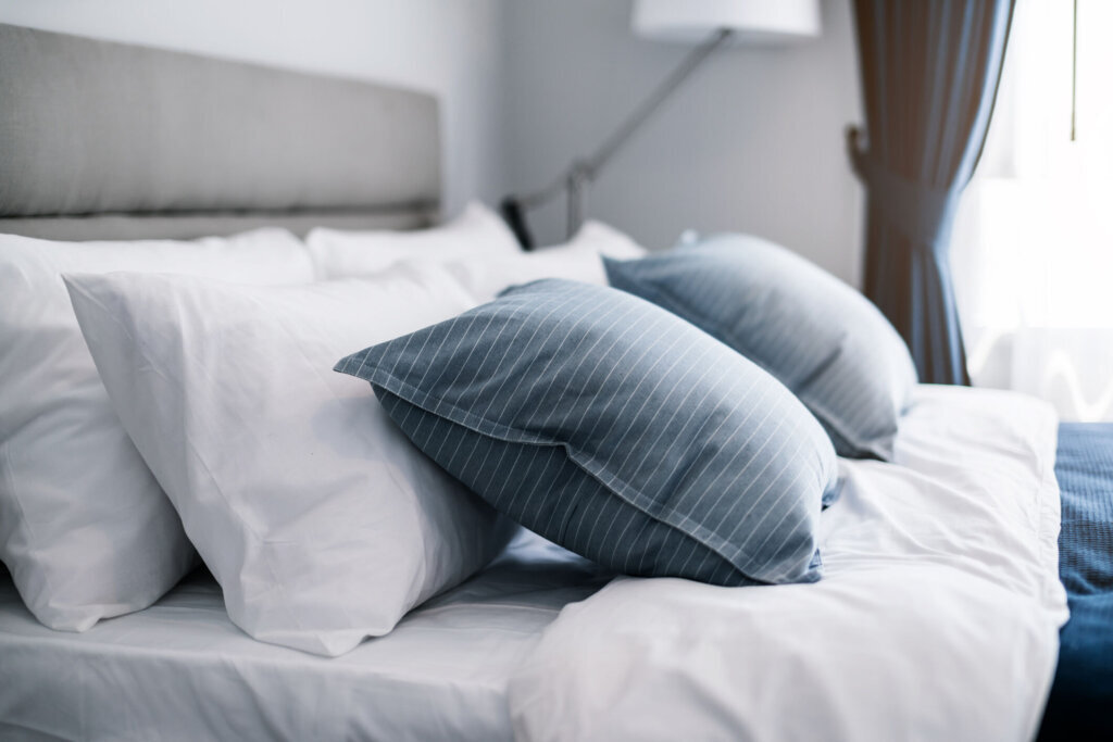 Bed maid up with clean white pillows and bed sheets in beauty room. Close up. Lens flair in sunlight.
