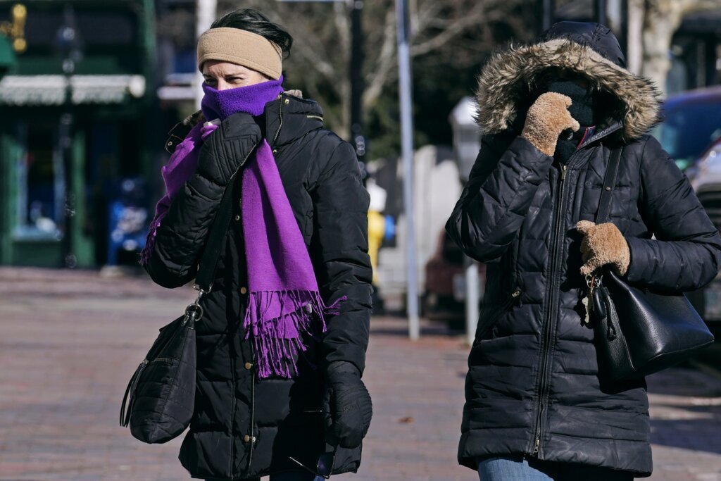 Two women are bundled up in cold weather clothing while walking during a frigid weather snap