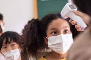 Teacher using thermometer for check temperature measurement on black girl forehead