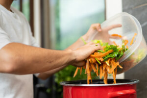 Young man making vegetable soup, broth, out of vegetable scraps