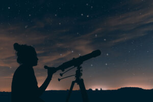 Woman with astronomical telescope. Night sky, with clouds and constellations