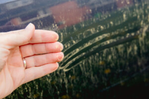 Person hand showing yellow pollen grains pulled from car. Trees and flowers pollen covering car exterior in spring, witch can damage your car's paint concept.