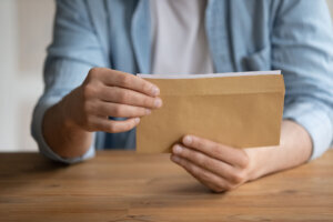 Close up young man getting business correspondence in envelope.