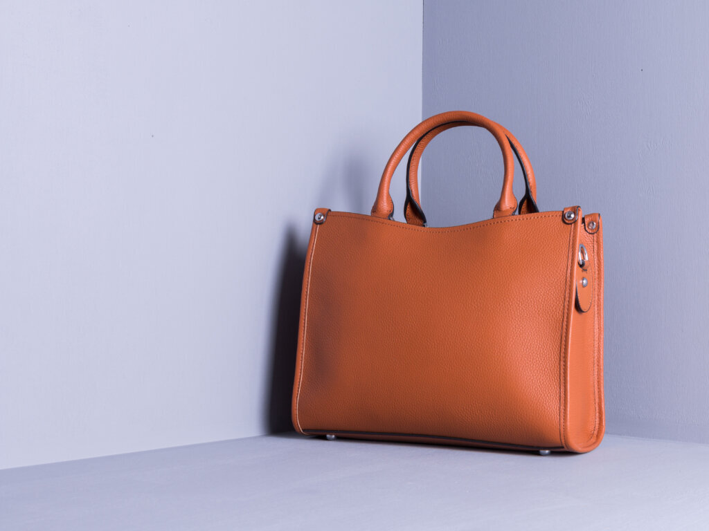 Women's bag of red color, genuine leather. Grey painted wooden background. Space for text