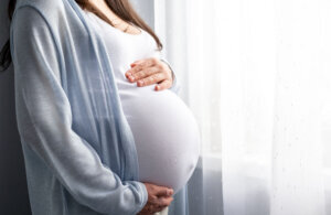 Healthy pregnancy. Side view pregnant woman with big belly advanced pregnancy in hands. Banner copyspace for text. Elegant mother waiting baby