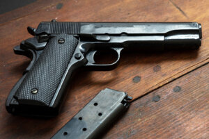 Pistol gun 9mm on wooden table. Auto metal weapon side view