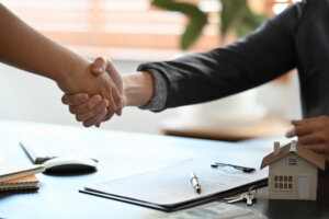 Young woman handshaking with real estate agent after signing contract.