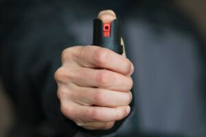 Man holding pepper spray (tear gas) in his hand. Self defense. Blur background, close up