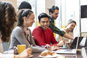 Young co workers multiethnic team planning a new startup Happy people working on a new project in creative coworking office Marketing concept Bright filter with focus on asian man face