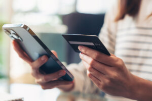 Woman hand holding credit cards and using smartphone for shopping online with payment on internet banking.