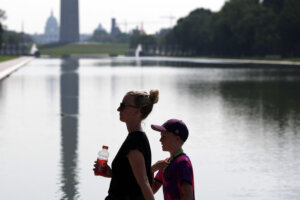 Mother and son walking past the Washington Monument in the heat.