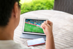 Watching soccer game on digital tablet.