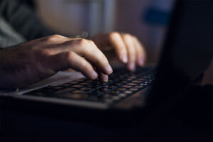 Man sitting at desk and working on laptop at night