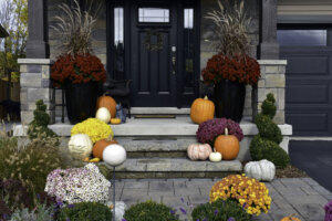 Residential autumn landscaping decor. Pumpkins, gourds and mum decorate the home entrance.
