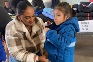 A woman zips up a young girls coat