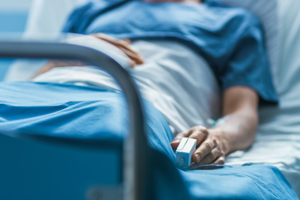 In the Hospital Sick Male Patient Sleeps on the Bed. Heart Rate Monitor Equipment is on His Finger.