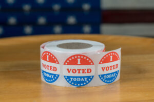 Roll of I Voted Today paper stickers on table with US Flag in background