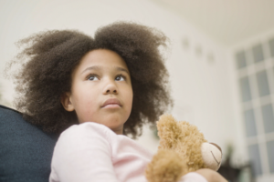 A stock photo of a foster child with a teddy bear.