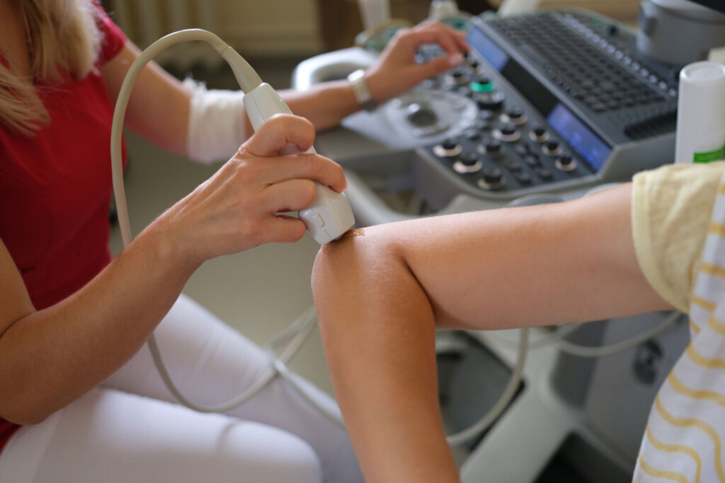 Doctor conducts an ultrasound examination of patient elbow in clinic