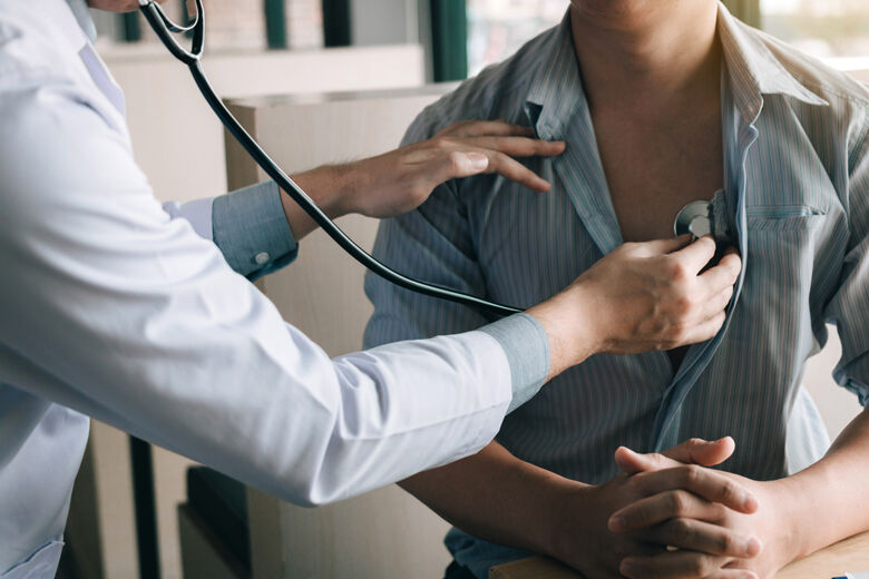 Asian doctor is using a stethoscope listen to the heartbeat of the elderly patient.