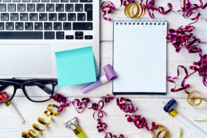 Office desk with laptop and open notepad decorated with party streamers