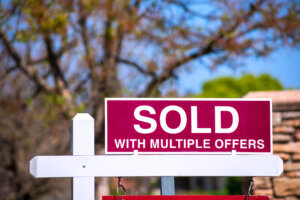 SOLD With Multiple Offers real estate sign near purchased house.
